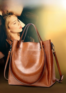 Macro view showing high-gloss oil wax leather texture and handle detail on brown tote bag