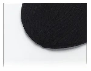 Detail of multi-panel top stitching and thick knit texture on a black winter beanie