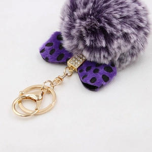 Macro view of purple faux fur pompom keychain with rhinestone leopard print bow