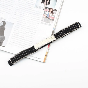 Dettaglio della cintura elastica nera con anelli dorati e fibbia decorativa con perle
