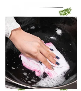 Action shot of cleaning a black iron pot with a soapy absorbent white fiber dishcloth