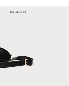 Detailopname van zwarte leren crossbodytas met gouden metalen gesp en brede schouderriem