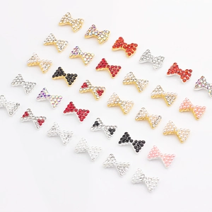 Gros plan de nœuds 3D pour nail art avec perles et strass colorés sur métal doré et argenté