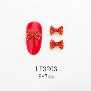 Vue macro des bijoux d'ongles nœud strass rouge 9x7mm avec base en alliage doré