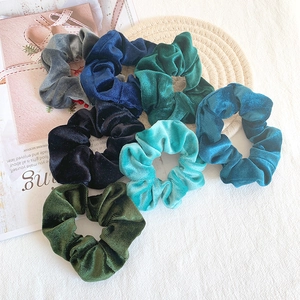 Detailed texture of seven multi-color velvet scrunchies displayed on a magazine