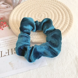 Macro shot of teal velvet scrunchie texture on a straw mat with aesthetic background