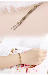 Detail of a two-tone gold and silver chain bracelet featuring a heart charm and extension