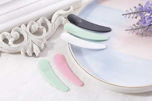 Cosmetic spatulas in black, mint green, white, and pink for skin care products