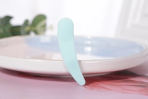 Detailed view of light blue cosmetic spatula placed on a decorative ceramic plate