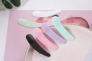 Set of colorful plastic cosmetic spatulas in a decorative plate with nature-themed background