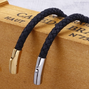 Vintage black leather braided bracelets with gold and silver steel clasps on wood