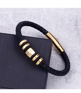 Detailed view of woven black leather strap and gold plated mantra charms on men's bracelet