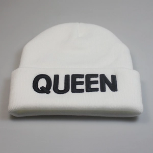 Detailed close-up of white knitted beanie featuring black QUEEN embroidery on the folded cuff