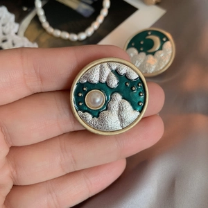 Vintage celestial round brooch featuring gold moon, silver clouds, and pearl on green enamel