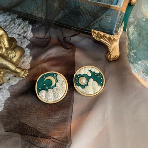 Detailed view of vintage star and moon earrings with green enamel and pearl accents