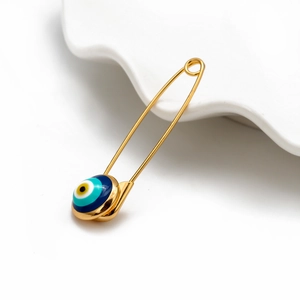 Minimalist golden Evil Eye brooch pin accessory displayed on a white ceramic tray