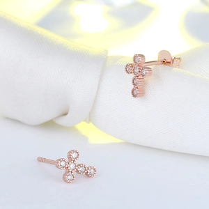 Close-up of rose gold S925 silver cross earrings with 4A cubic zirconia on white silk