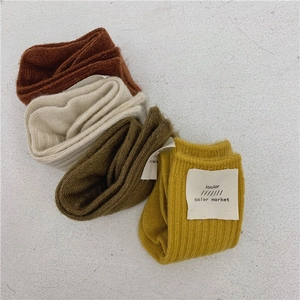 Detail of four pairs of ribbed wool socks in brown, beige, olive green, and mustard yellow