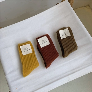 Detailed view of three pairs of thick ribbed wool socks with woven brand labels