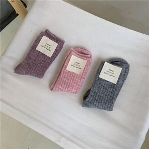 Detailed texture of thick wool blend socks in grey, pink, and purple knitted fabric