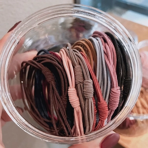 Close-up of colorful high-elastic braided hair ties organized in a clear storage jar