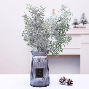 Artificial cedar branch with white frosted snow finish in vase for Christmas decor