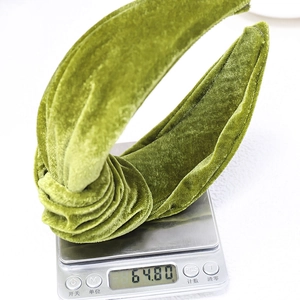 Detailed view of a knotted green velvet headband being weighed on a digital scale