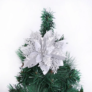Close-up of a silver glitter hollow Christmas flower ornament on a green tree branch