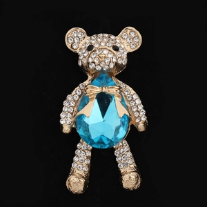 Macro shot of gold crystal bear accessory with sky blue gemstone and pavé rhinestones