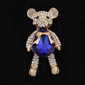 Detailed close-up of golden bear brooch with blue crystal and shimmering white rhinestones