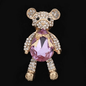 Macro shot of a gold teddy bear charm with white rhinestones and a pink teardrop crystal