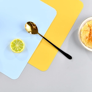 Modern gold spoon with black handle on Morandi silicone placemats in blue and yellow