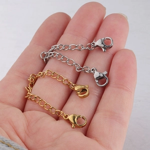Set of gold and silver stainless steel necklace extenders with lobster clasps on a palm