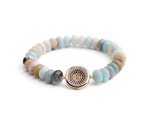 Macro detail of natural stone beaded bracelet featuring a gold micro-set evil eye charm