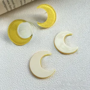 Close-up of yellow glitter and cream acrylic moon studs for DIY jewelry making