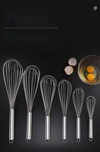 Detail of stainless steel whisks in various sizes with hanging loops on black background
