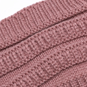 Close-up of thick knitted texture in rose pink showing soft wool fibers and warm rib pattern