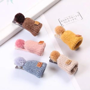 Close-up of five mini knitted hat hair clips in soft Morandi colors with plush pom-poms