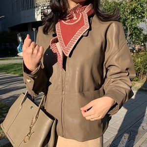 Detalle de bufanda roja con patrón H combinada con chaqueta de cuero marrón y bolso gris