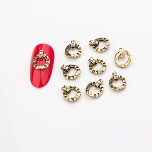 Macro detail of retro gold alloy nail charms with LOVE engraving and colorful rhinestones