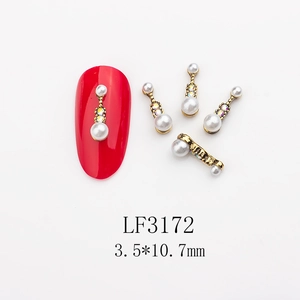 Detail of pearl and rhinestone nail art charms with gold metal base on red nails
