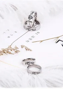 Detail of silver couple rings with I Love You engraving on elegant feather background
