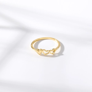 Detailed view of gold plated ring featuring three linked hollow heart designs on white background