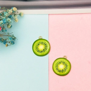 Macro detail of two kiwi fruit slice charms with gold metal edges for DIY jewelry