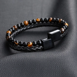 Detail of double-layer bracelet with black braided leather, tiger eye beads and black clasp