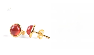Macro shot of circular red natural stone earrings with gold alloy and small crystals
