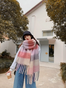Street style shot of a woman wearing a thick rainbow plaid tassel scarf in soft cashmere
