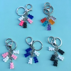 Top view of colorful resin gummy bear keychains in pink blue and white on a blue background