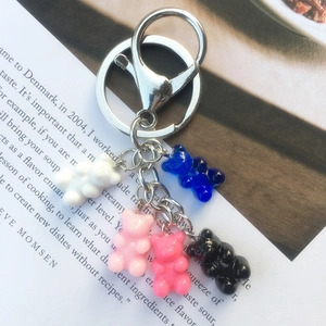 Detail of five colorful resin bear charms on a metallic keychain over text background
