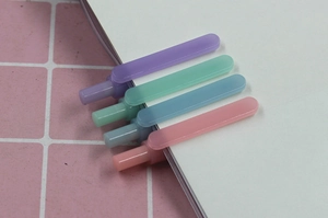 Detailed view of pastel cartoon pencils in four colors clipped to a notebook edge